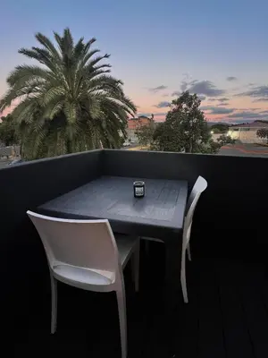 a table and chairs on a balcony with a palm tree at Marbella - Cozy studio in Heart of Table View in Cape Town