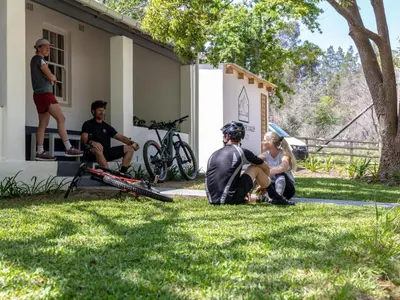 a group of people sitting on the grass outside a house at Jonkershoek Valley Cottage in Stellenbosch