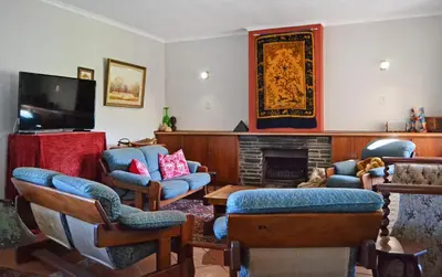 a living room with a fireplace and a tv at Chesham House in Hermanus