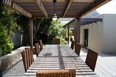 a long wooden table with chairs on a deck at Knight's House in Hermanus