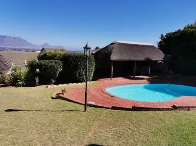a house with a swimming pool and a thatch roof at Plattekloof Treasures in Cape Town