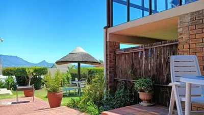 a patio with a table and chairs and an umbrella at Plattekloof Treasures in Cape Town