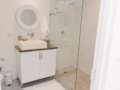 a white bathroom with a sink and a shower at McLeod's & Stuart's Cottage in Somerset West