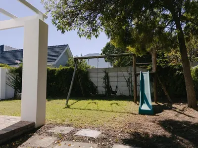 a swing set in a yard with a tree at McLeod's & Stuart's Cottage in Somerset West