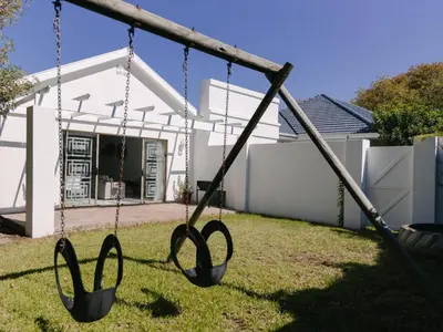 two swings in a yard in front of a house at McLeod's & Stuart's Cottage in Somerset West