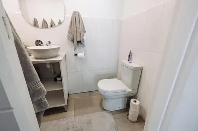 a white bathroom with a toilet and a sink at McLeod's & Stuart's Cottage in Somerset West