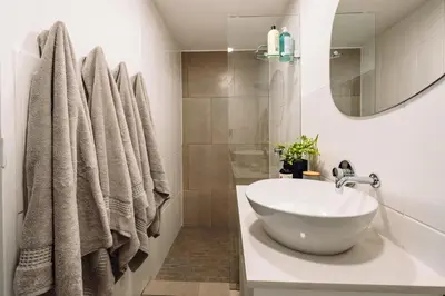 a white bathroom with a sink and a mirror at McLeod's & Stuart's Cottage in Somerset West