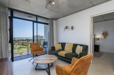a living room with a couch and a table and chairs at Sea and Sun-Table Mountain views Wifi Parking! in Cape Town