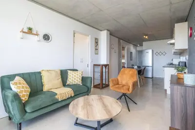 a living room with a green couch and a table at Sea and Sun-Table Mountain views Wifi Parking! in Cape Town