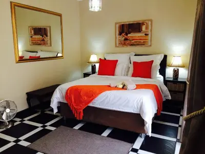 a bedroom with a large bed with red pillows at Helderberg Guesthouse in Gordonʼs Bay