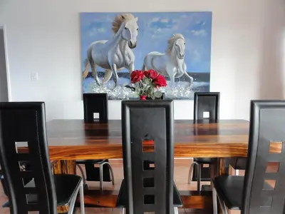 a dining room table with a painting of horses on it at Helderberg Guesthouse in Gordonʼs Bay