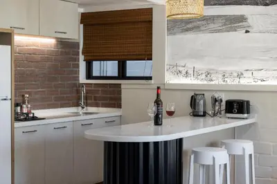 a kitchen with a counter with two glasses of wine at Hornbill House Self Catering Accommodation in Hermanus