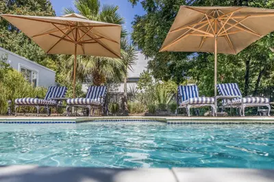 a group of chairs and umbrellas next to a pool at Petit Ermitage in Franschhoek