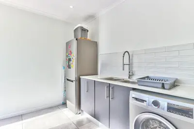 a kitchen with a refrigerator and a washing machine at Family Home, WiFi, Patio, Secure Parking in Cape Town
