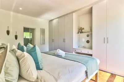 a bedroom with a large white bed with blue pillows at Family Home, WiFi, Patio, Secure Parking in Cape Town