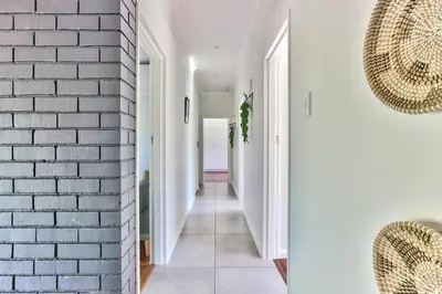 a hallway with white walls and a brick wall at Family Home, WiFi, Patio, Secure Parking in Cape Town