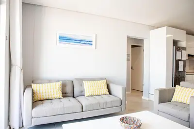a living room with a couch and two chairs at Beachfront 2 bed w swimming pool, Blouberg 54 Beach Break in Bloubergstrand
