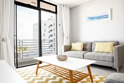 a living room with a couch and a table at Beachfront 2 bed w swimming pool, Blouberg 54 Beach Break in Bloubergstrand