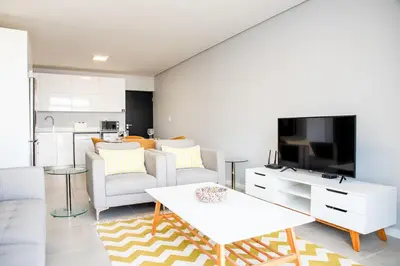 a living room with a couch and a tv at Beachfront 2 bed w swimming pool, Blouberg 54 Beach Break in Bloubergstrand