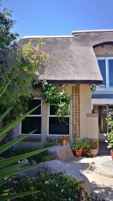 a small house with a thatched roof and some plants at Teas & Seas Self Catering Cottage in Cape Town