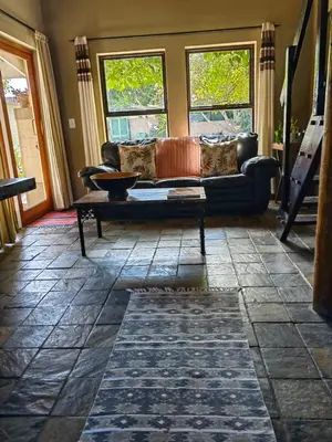 a living room with a couch and two windows at Teas & Seas Self Catering Cottage in Cape Town