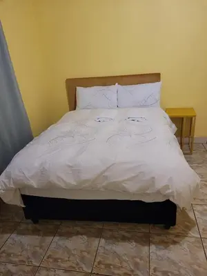 a bed with white sheets and two candles on it at Jacmo Guest Private Rooms in Cape Town