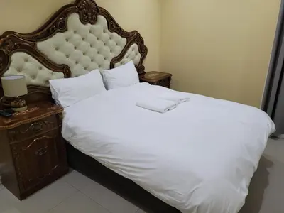 a bedroom with a white bed with a large headboard at Jacmo Guest Private Rooms in Cape Town