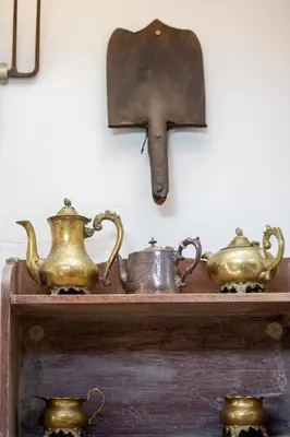 a shelf with three tea pots and a clock on a wall at Art Box in Greyton