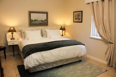 a bedroom with a large bed with two lamps and a window at Die Kelderhuis in Breerivier