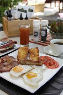 a plate of breakfast food with eggs sausage and tomatoes at Die Kelderhuis in Breerivier