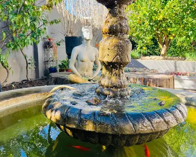 a fountain with a statue of a man sitting in a garden at Spacious Stays Apartment in Paarl