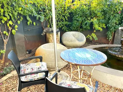 a table and chairs with an umbrella in a garden at Spacious Stays Apartment in Paarl