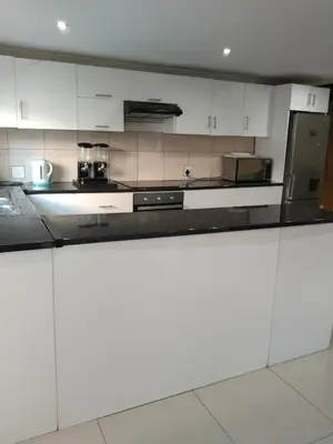 a kitchen with white cabinets and a black counter top at On the Wrench in Cape Town