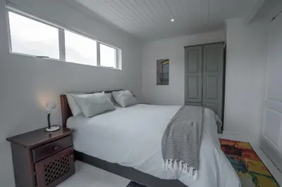 a white bedroom with a bed and a window at Stony Point Beach House in Clareport