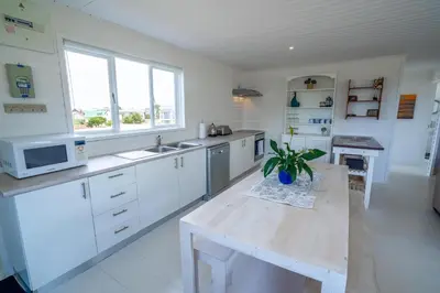 a kitchen with white cabinets and a table with a plant at Stony Point Beach House in Clareport