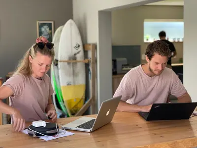 a man and woman sitting at a table with laptops at Boardrooms Kite Accommodation in Cape Town
