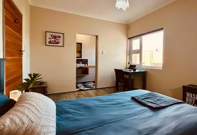 a bedroom with a bed and a desk and a window at Boardrooms Kite Accommodation in Cape Town