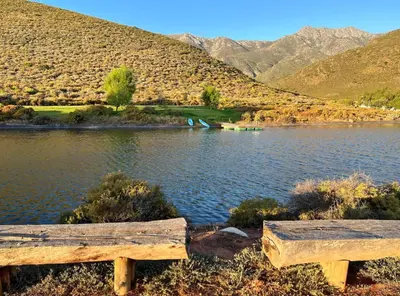a bench next to a lake with mountains in the background at Penhill Farm East Grange in Nuy