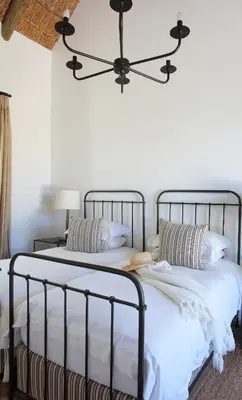 a bedroom with two beds with white sheets and a chandelier at Penhill Farm East Grange in Nuy