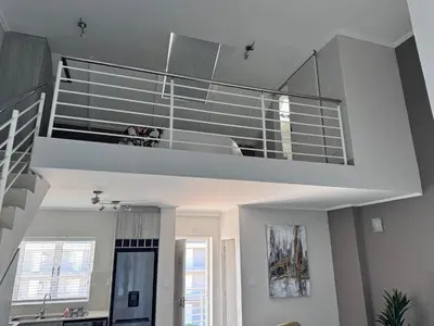 a living room with a staircase in a house at Beautifully furnished loft apartment in central Durbanville in Durbanville