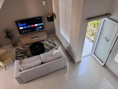 a living room with a couch and a flat screen tv at Beautifully furnished loft apartment in central Durbanville in Durbanville