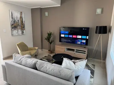 a living room with a couch and a flat screen tv at Beautifully furnished loft apartment in central Durbanville in Durbanville
