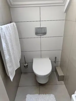 a white bathroom with a toilet and a towel at Beautifully furnished loft apartment in central Durbanville in Durbanville