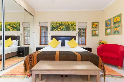 a bedroom with a bed and a red chair at Kleinbosch Lodge in Stellenbosch