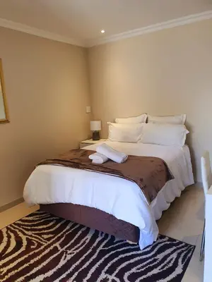 a bedroom with a large bed with white sheets and pillows at ELMED GUEST HOUSE in Cape Town