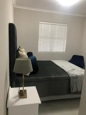 a bedroom with a bed and a lamp on a table at MLMK Property Studio17 in Cape Town