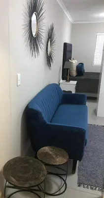 a blue couch in a living room with a mirror at MLMK Property Studio17 in Cape Town