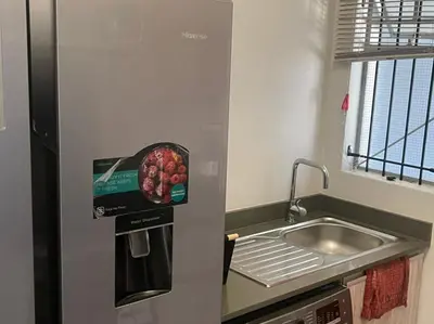 a kitchen with a sink and a refrigerator with a basket of fruit at Eden Heights in Cape Town