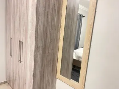 a wooden cabinet with a mirror in a room at Eden Heights in Cape Town