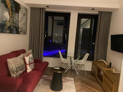 a living room with a red couch and chairs and a window at Bridgewater one luxury Apartment in Cape Town